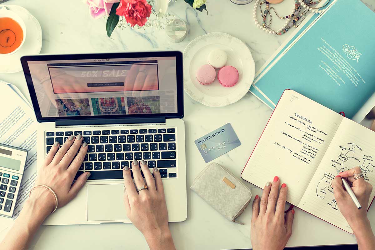 One Person On a Laptop and Another Writing In a Notebook