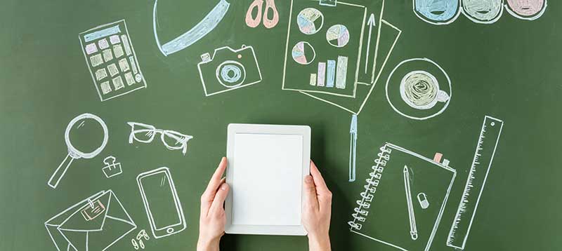 Hands holding a tablet over chalk drawings of tools