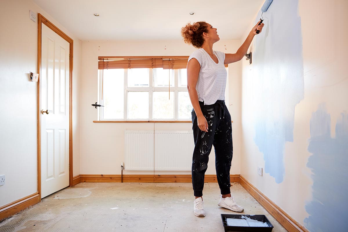 Woman Decorating Room In New Home Painting Wall